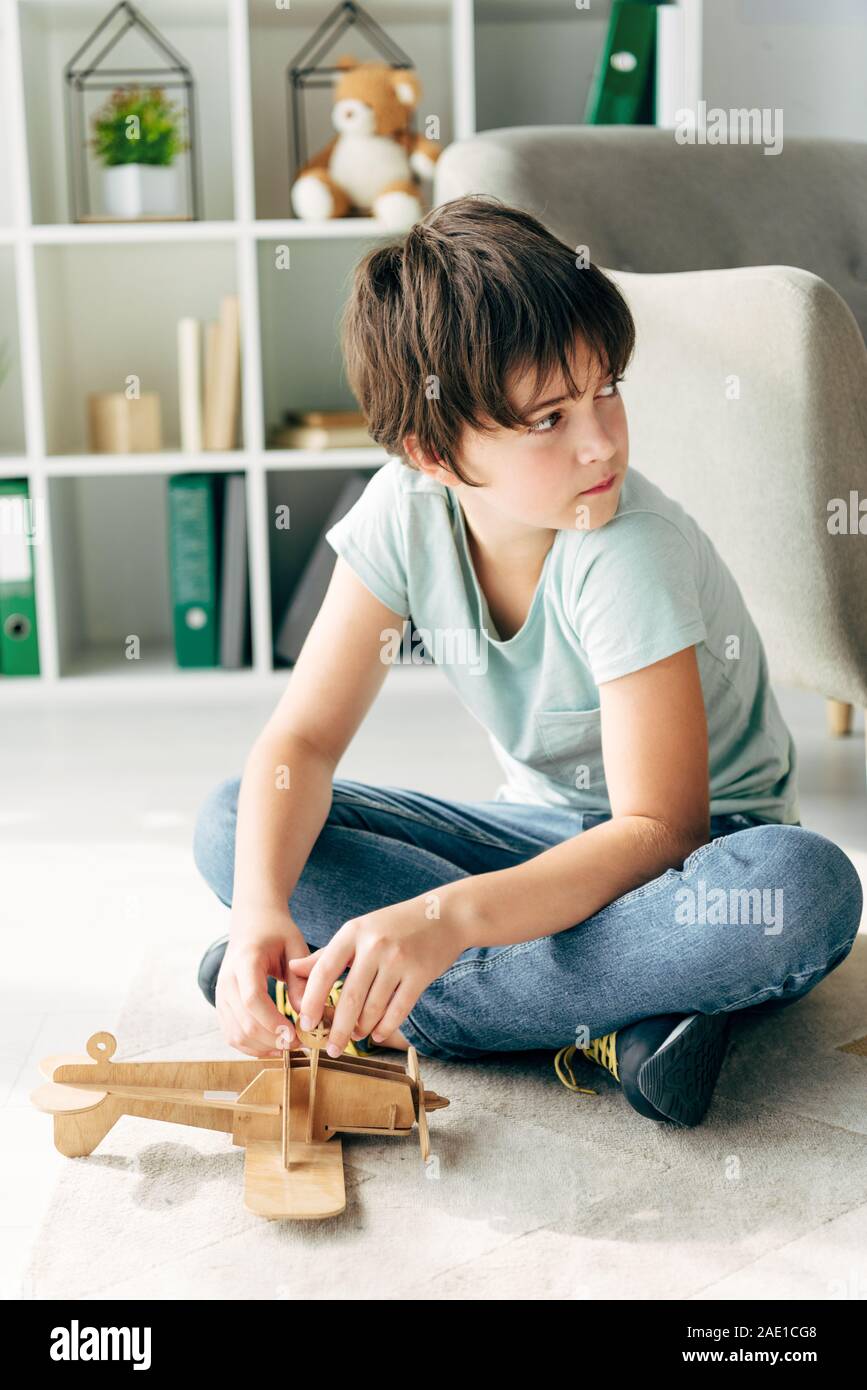 kid with dyslexia sitting on floor and holding wooden plane Stock Photo ...