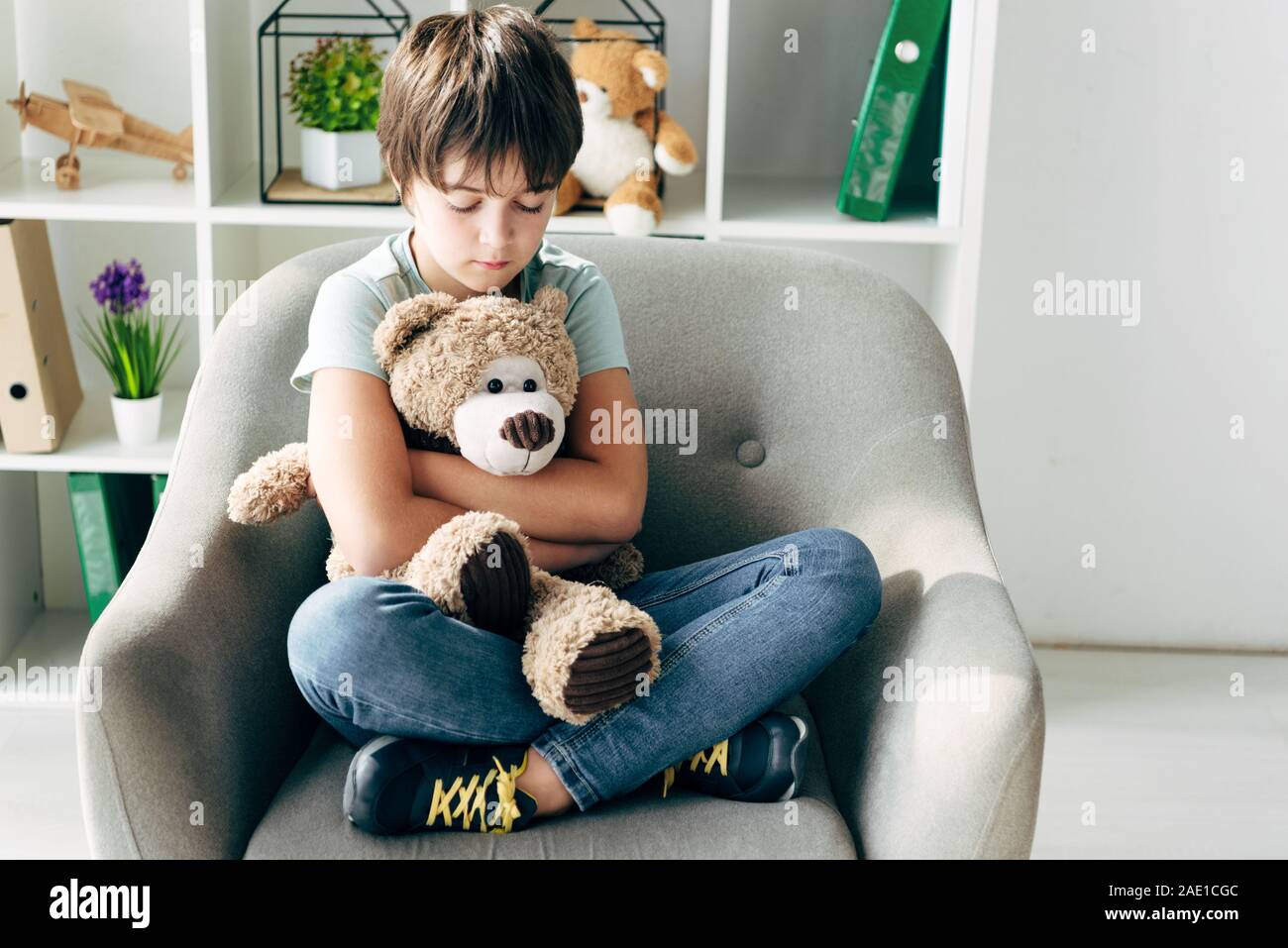 kid with dyslexia holding teddy bear and sitting on armchair Stock ...