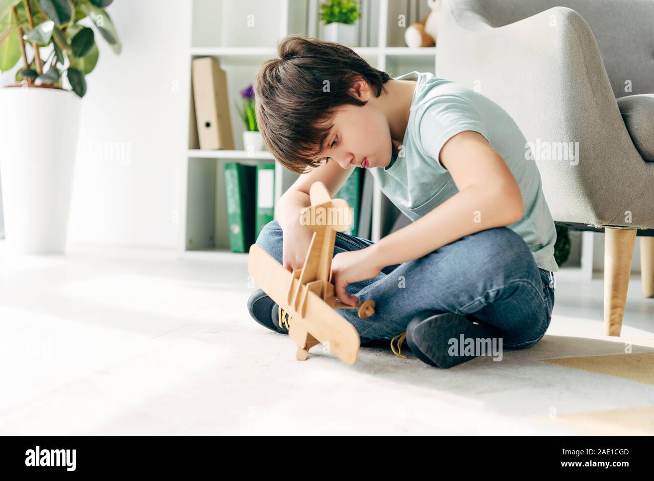 kid with dyslexia sitting on floor and holding wooden plane Stock Photo ...