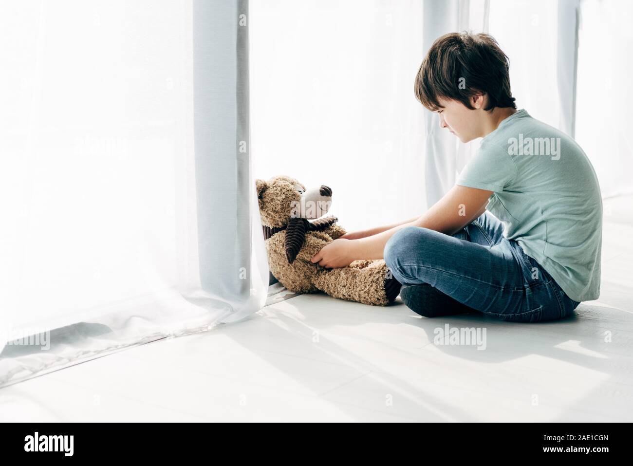 kid with dyslexia sitting on floor and looking at teddy bear Stock ...