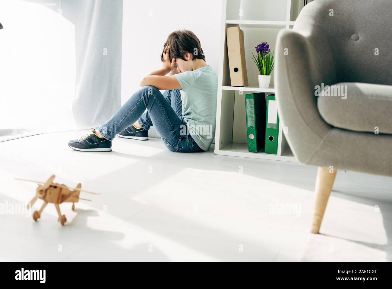 side view of sad kid with dyslexia sitting on floor Stock Photo - Alamy