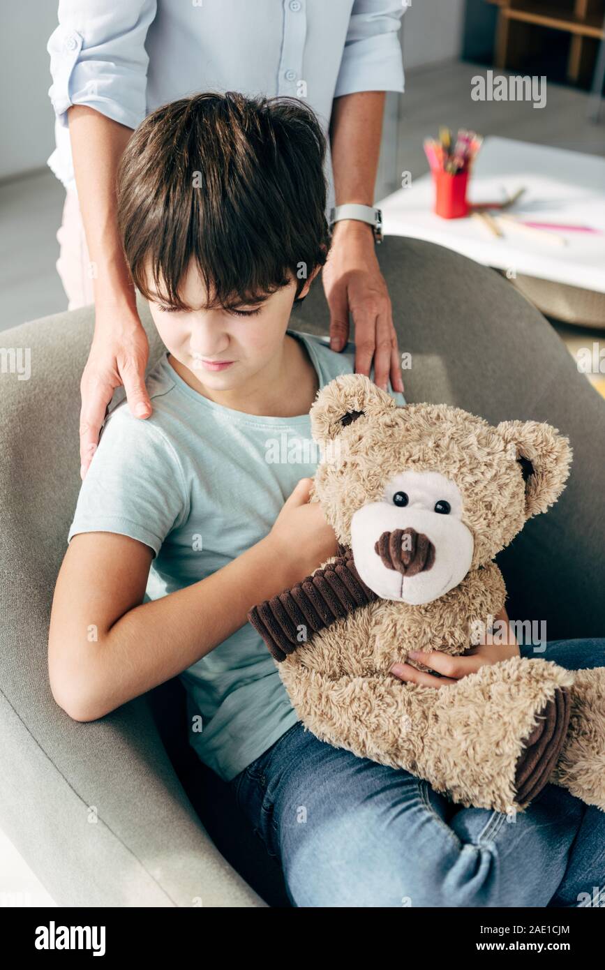 cropped view of child psychologist hugging kid with dyslexia holding ...