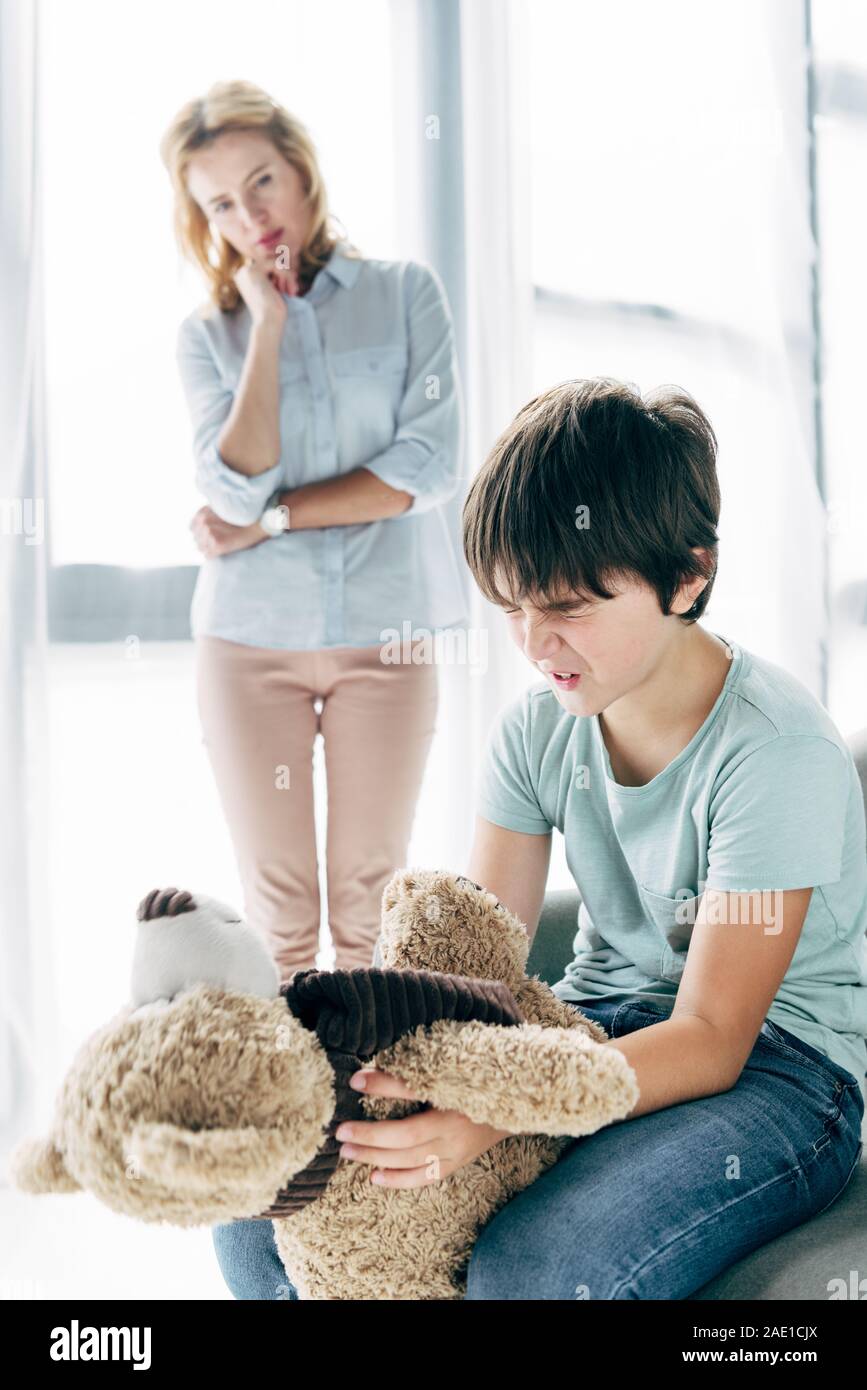 sad kid with dyslexia holding teddy bear and child psychologist looking ...
