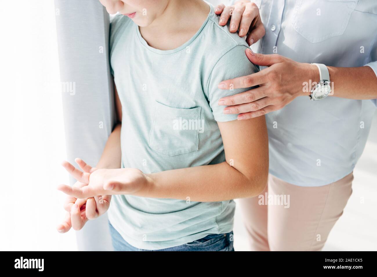 cropped view of child psychologist hugging kid with dyslexia Stock