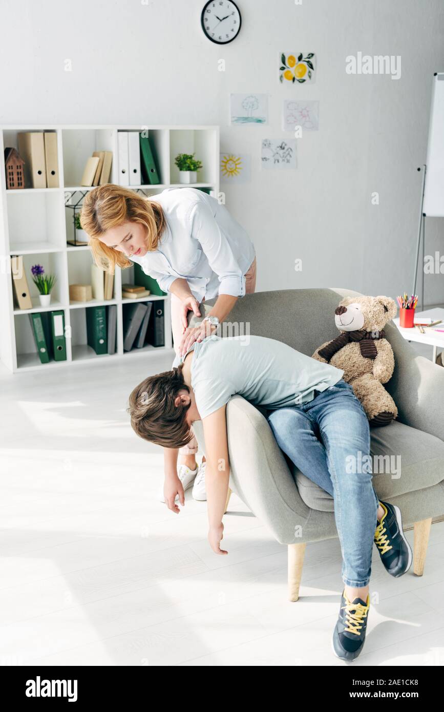 sad kid with dyslexia sitting on armchair and child psychologist ...