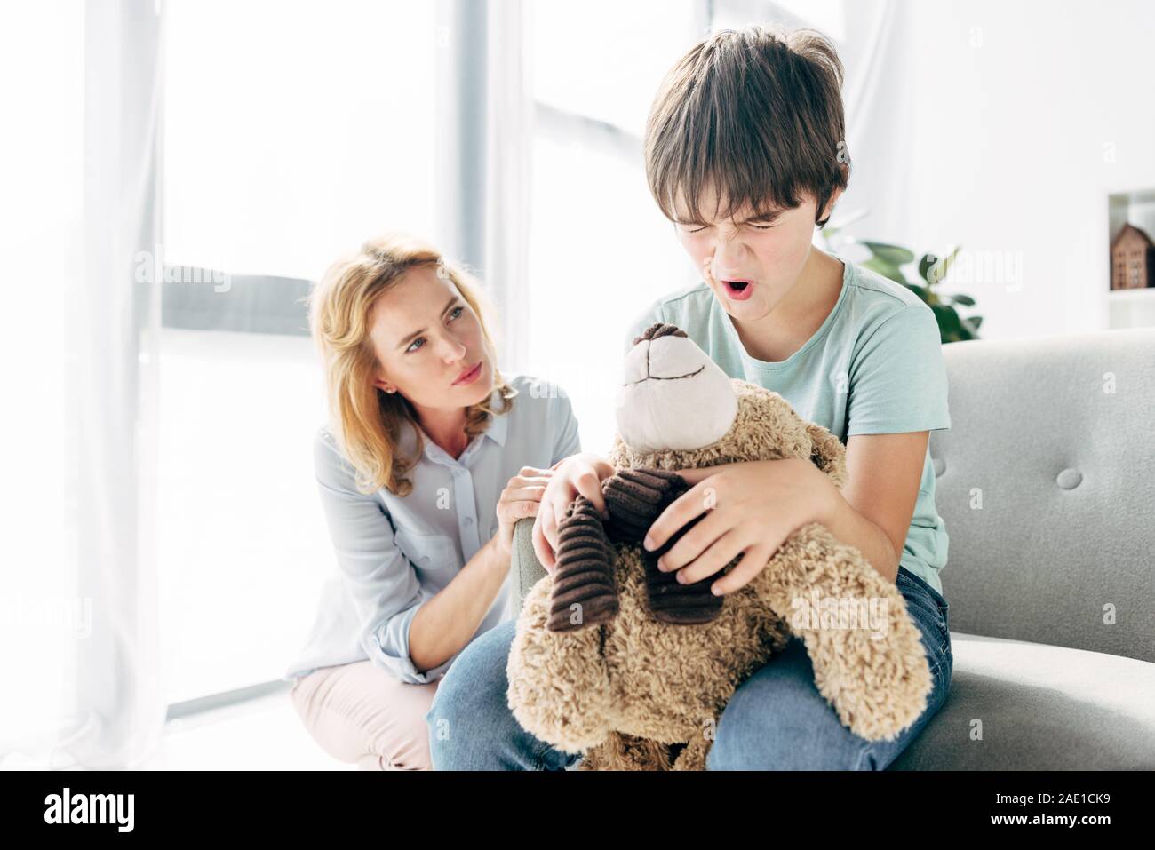 irritated kid with dyslexia holding teddy bear and child psychologist ...