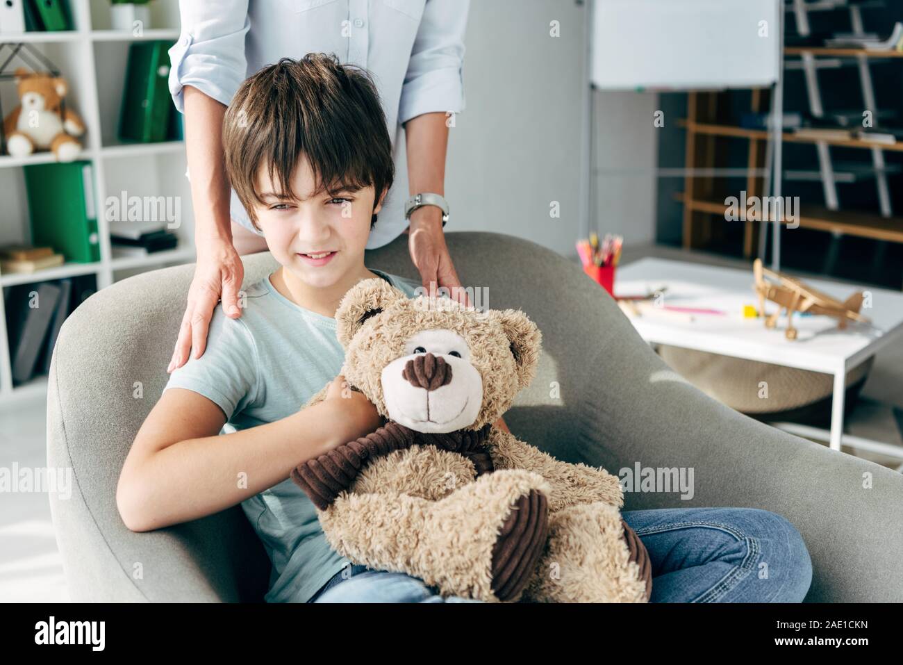 cropped view of child psychologist hugging kid with dyslexia holding ...