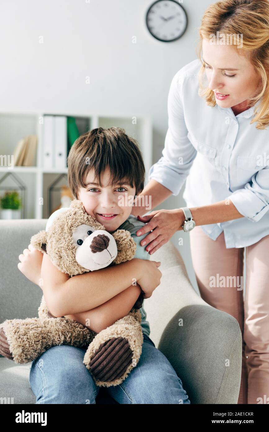 smiling kid with dyslexia holding teddy bear and child psychologist ...