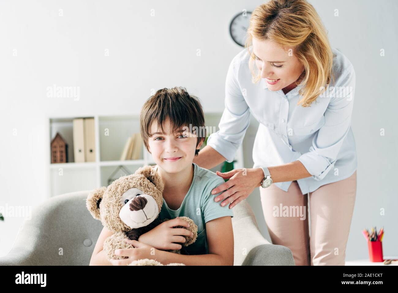 smiling kid with dyslexia holding teddy bear and child psychologist ...