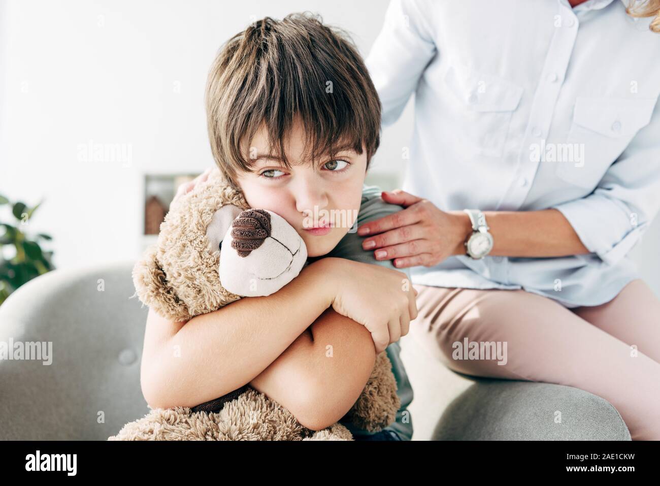 sad kid with dyslexia holding teddy bear and child psychologist hugging ...