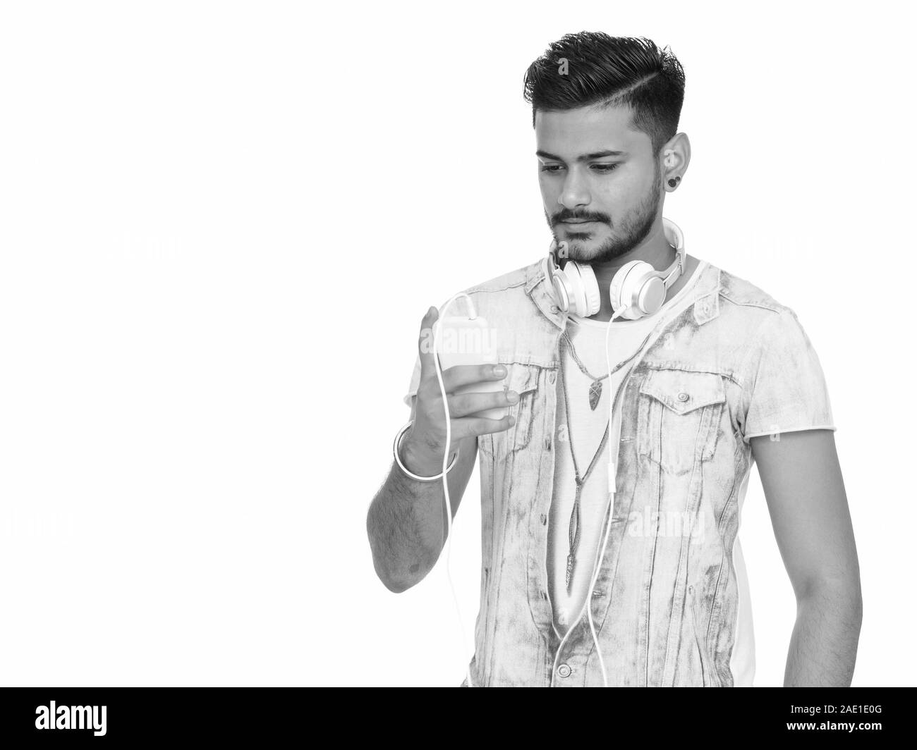Young handsome Indian man using mobile phone with headphones Stock ...