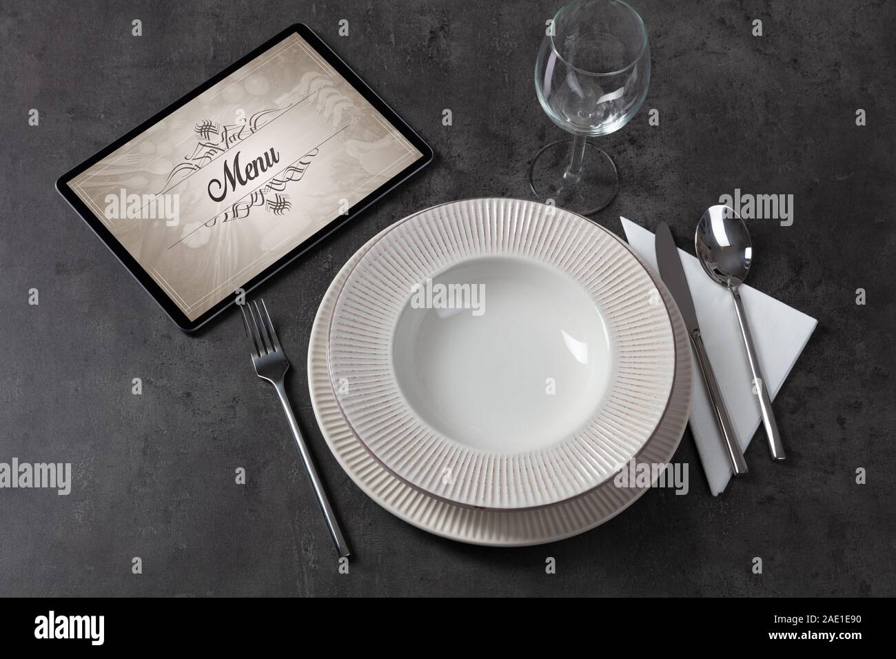 Tablet with stylish restaurant logo and laid table Stock Photo
