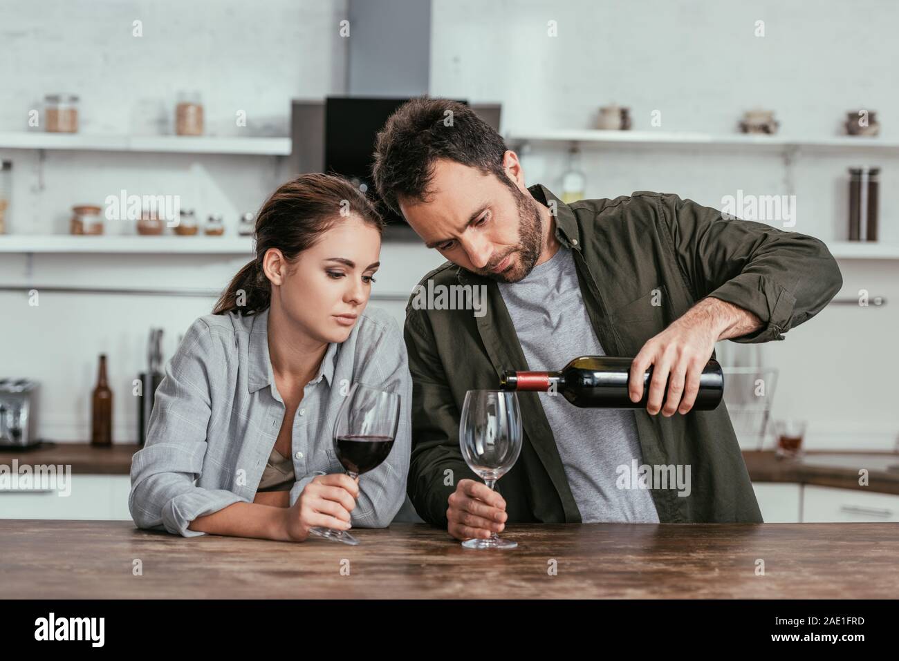 Alcohol dependent couple pouring red wine on kitchen Stock Photo