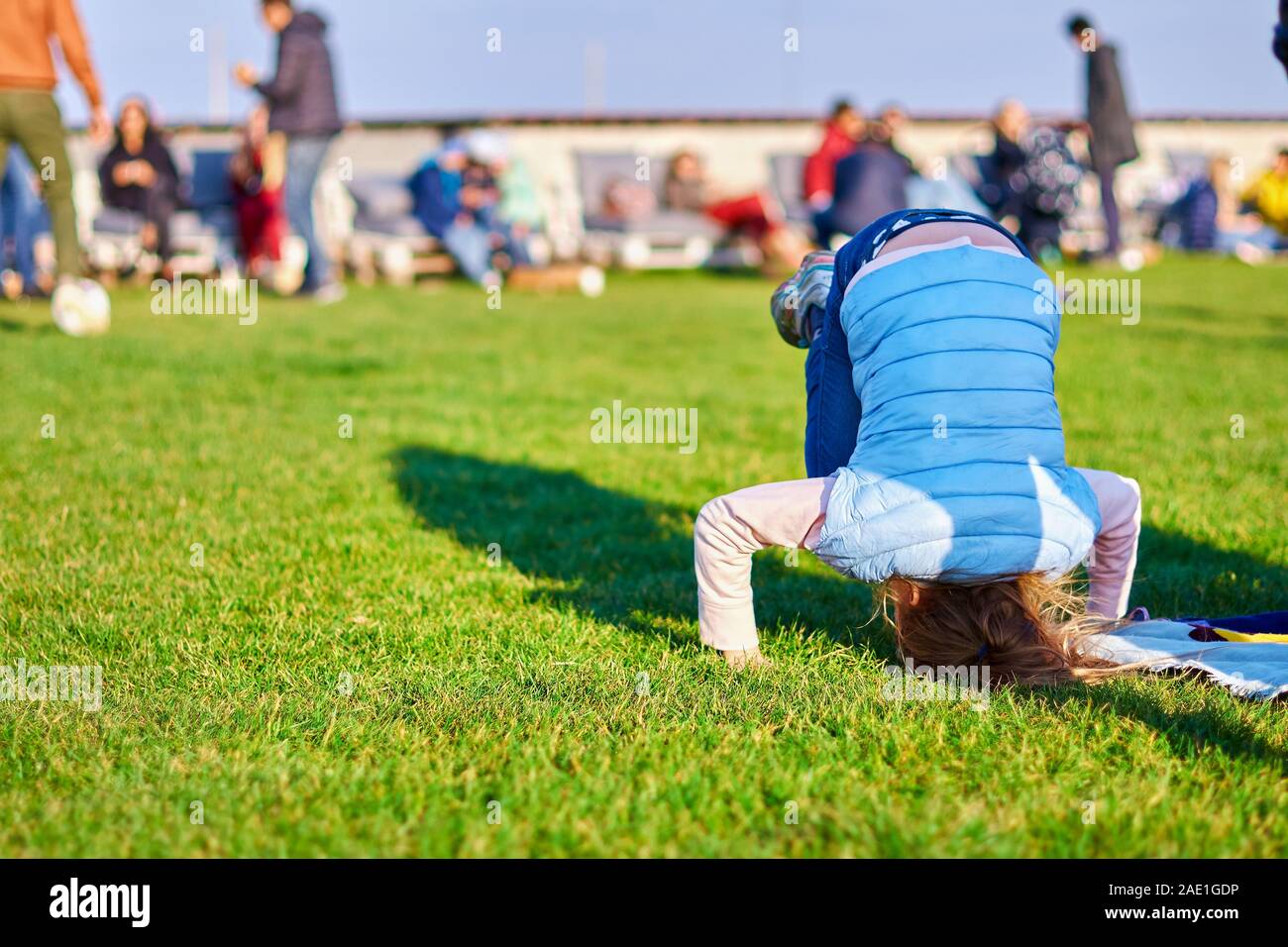 little girl standing on her head on the grass in the park. Child Stock ...