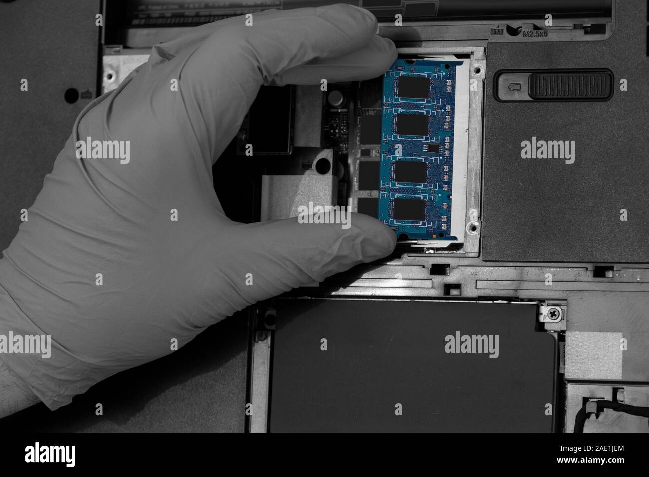 Technician installing RAM into the memory slot on a laptop computer.  Abstract image with selective colour Stock Photo