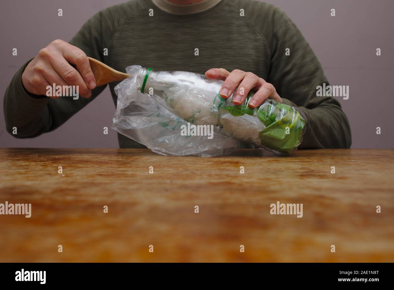 Making an eco brick stuffing plastic packaging waste into a plastic bottle. Stock Photo