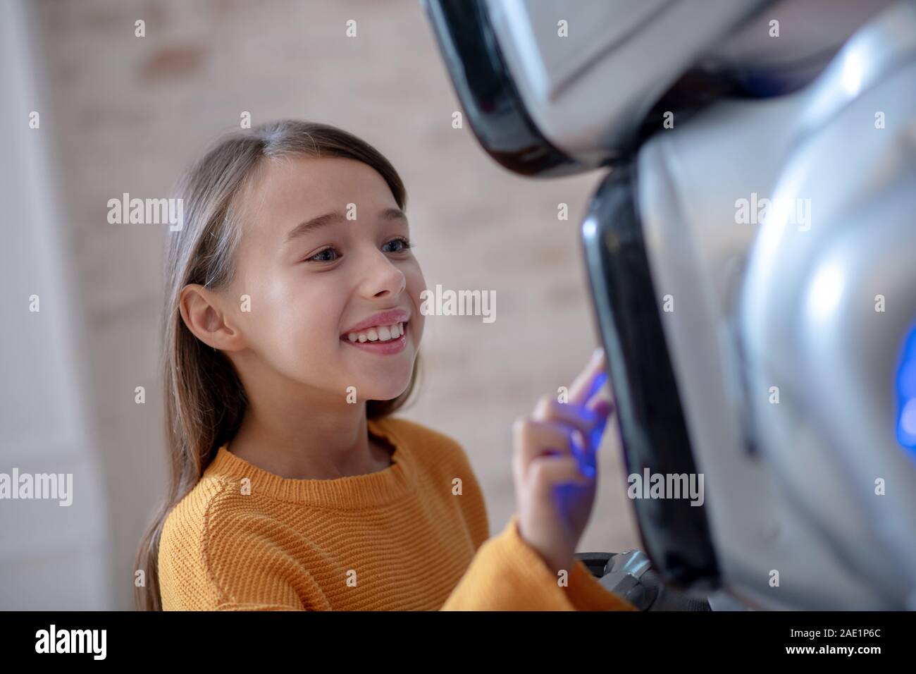 Beaming cute girl programming her house robot Stock Photo - Alamy