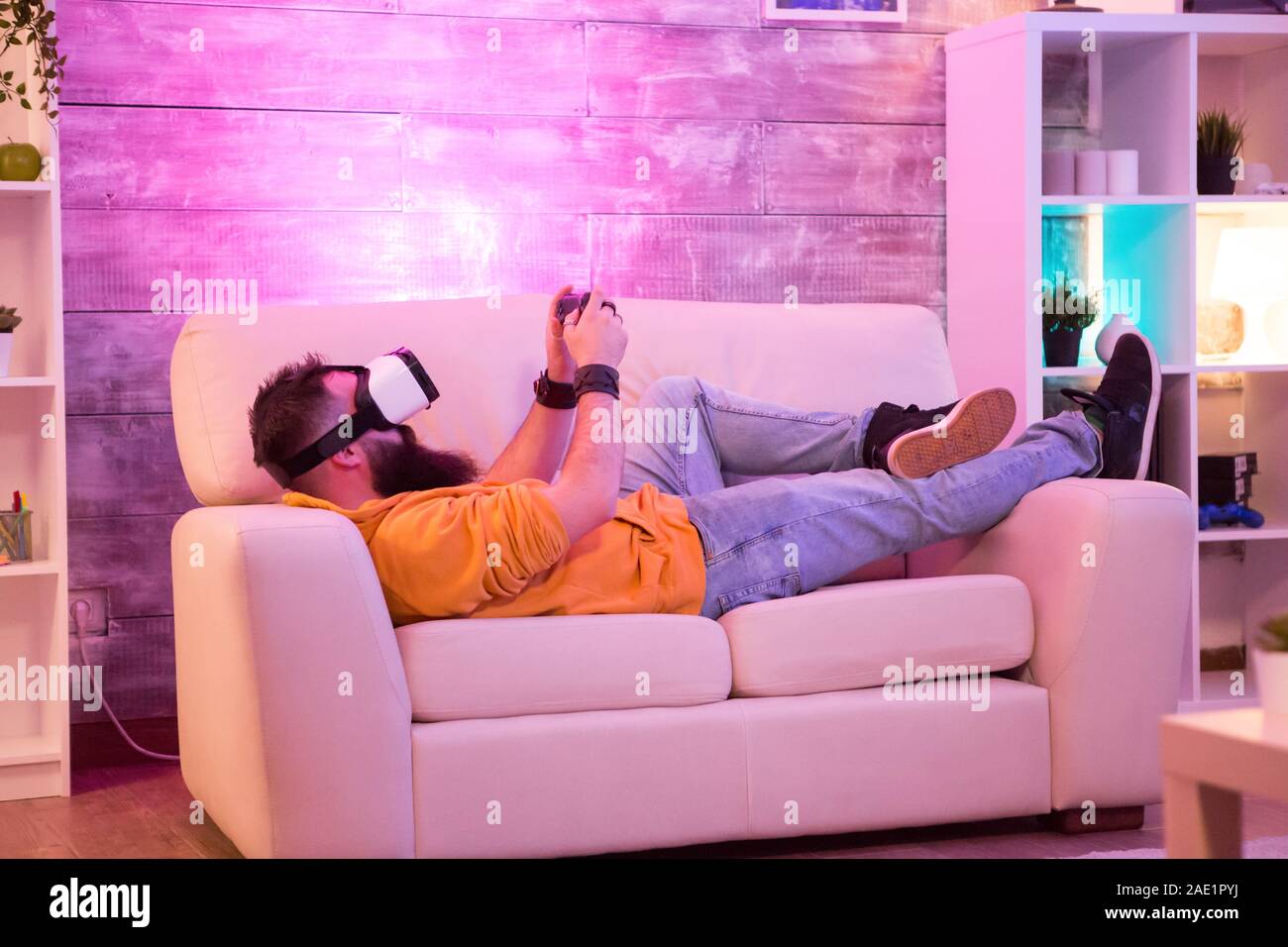 Man playing games using virtual reality goggles while sitting on sofa
