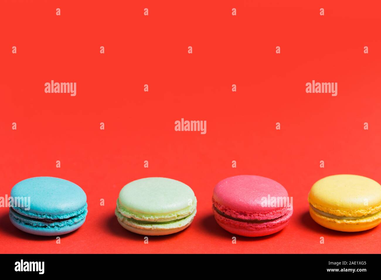 Sweet and colourful french macaroons or macaron on red background with copy space. Dessert, homemade cake Stock Photo