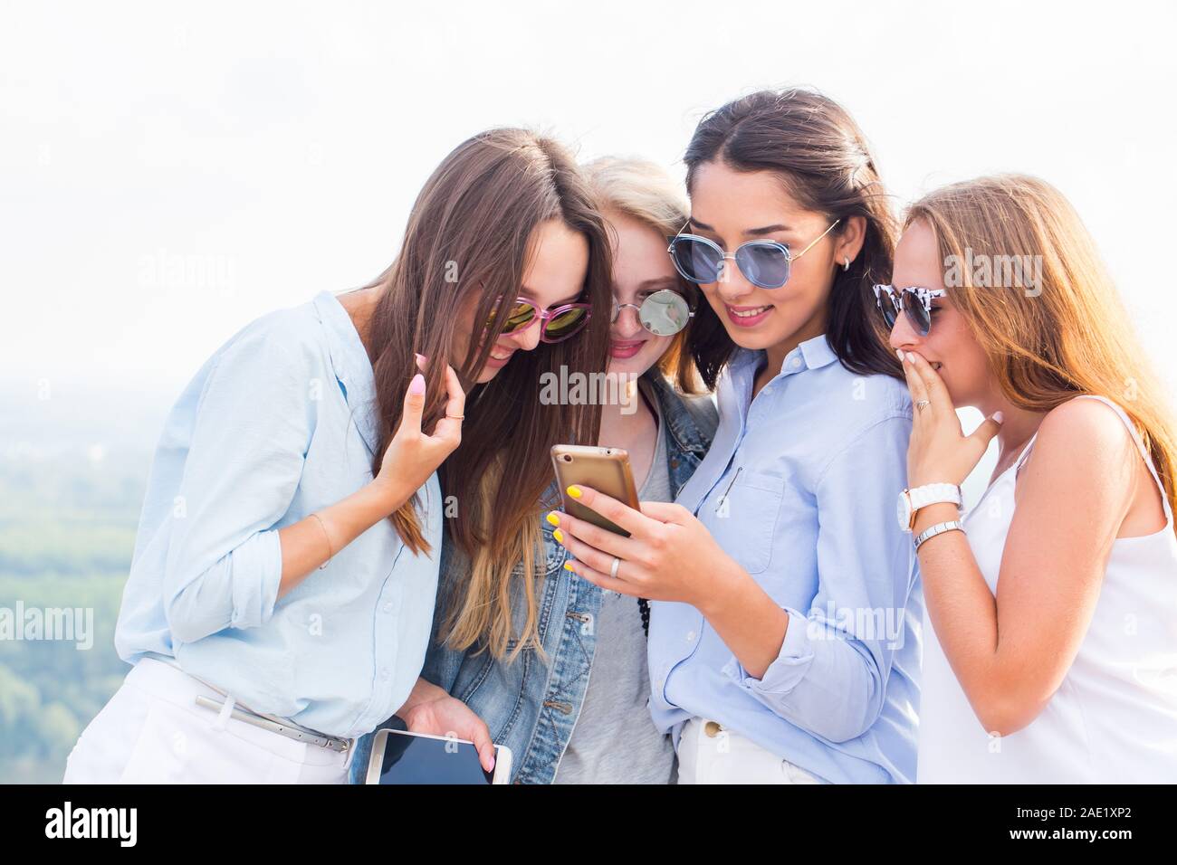 A group of beautiful girls look at the phone girlfriend and laugh, surprise...