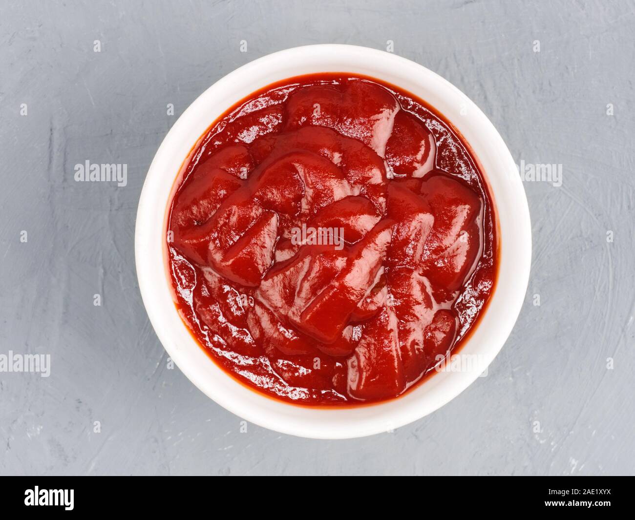Tomato paste in a white bowl on a gray concrete background. Healthy eating concept Stock Photo