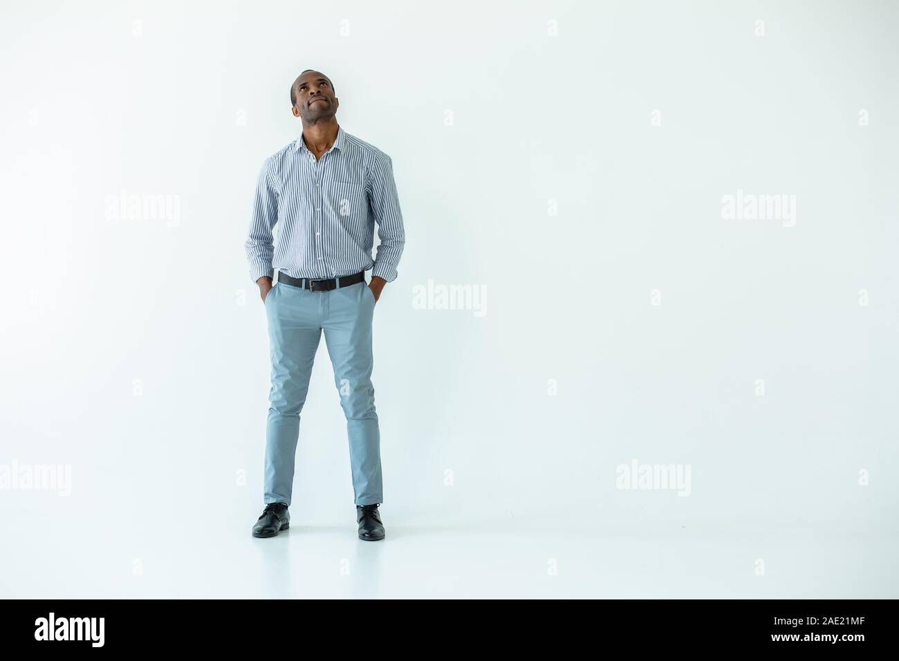 Thoughtful man standing against white background Stock Photo - Alamy