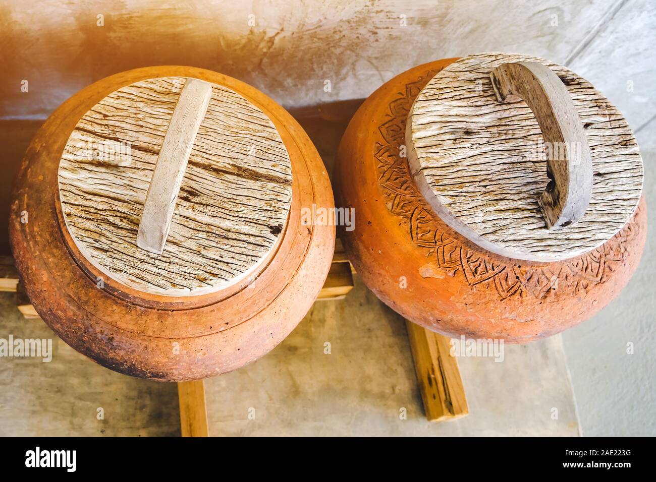 Row of earthen jars with wood lids and rough gray floor for water