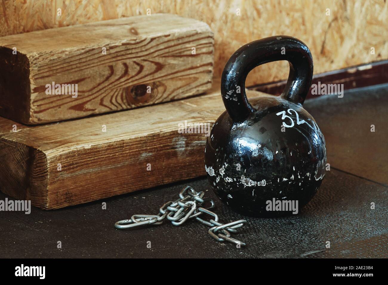 Old kettlebell covered in chapped glossy black paint standing on dusty