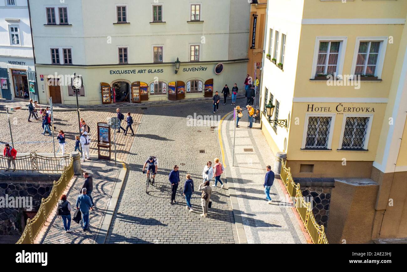Tourists walking over cobblestone bridge over The Čertovka canal, Hotel Čertovka and souvenir shop in Lesser Town Prague Czech Republic. Stock Photo