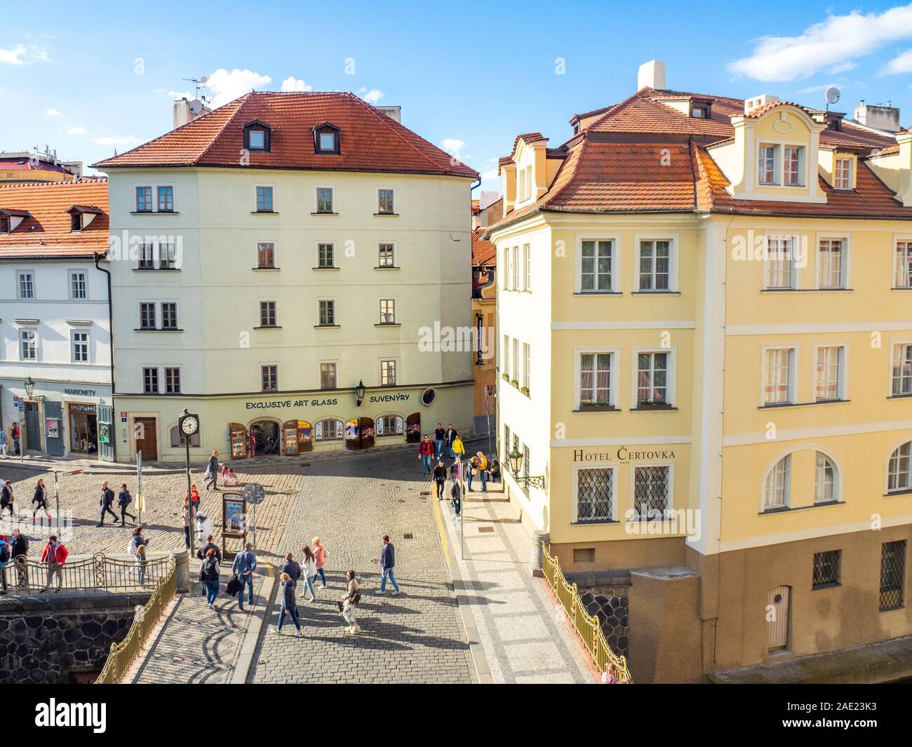 Tourists walking over cobblestone bridge over The Čertovka canal, Hotel Čertovka and souvenir shop in Lesser Town Prague Czech Republic. Stock Photo