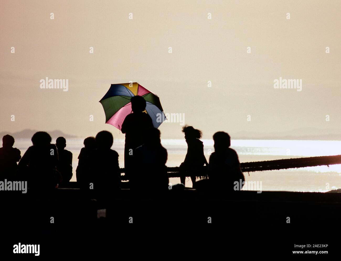 Fiji.  Silhouette of group of people on sea wall at sunset. Stock Photo