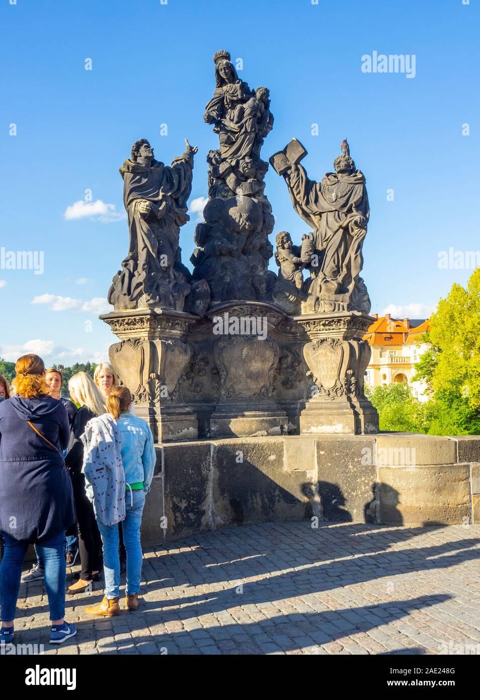 Tourists standing by replica statues of Madonna, Saint Dominic and Thomas Aquinas on the Charles Bridge Prague Czech Republic. Stock Photo