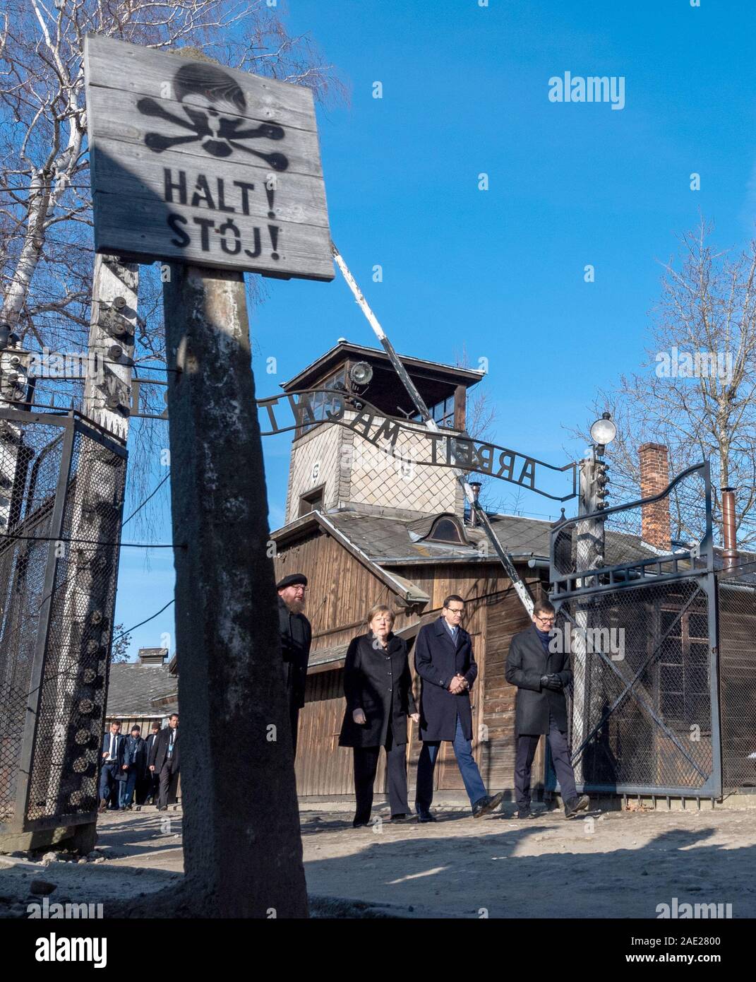 06 December 2019, Poland, Oswiecim: Federal Chancellor Angela Merkel (CDU) visits the former German Auschwitz concentration camp and walks under the entrance gate with the words 'Arbeit macht frei' (Work makes free) together with Polish Prime Minister Mateusz Morawiecki (to the right of Merkel) and Piotr Cywinski (to the left of Merkel), Director of the Auschwitz-Birkenau Memorial and President of the Auschwitz-Birkenau Foundation. Andrzej Kacorzyk, Deputy Director of the Auschwitz-Birkenau Museum, goes to the far right. Merkel accepted an invitation from the Auschwitz-Birkenau Foundation, whi Stock Photo