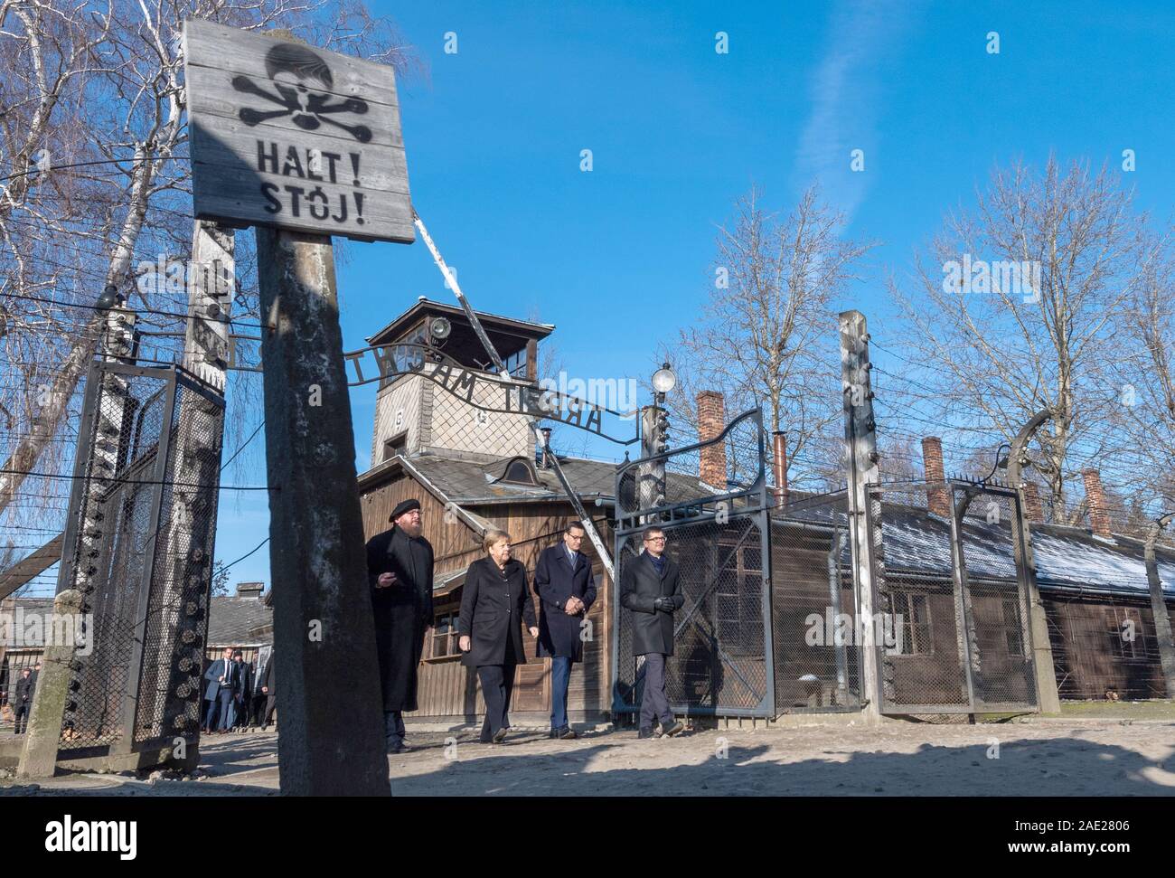 06 December 2019, Poland, Oswiecim: Federal Chancellor Angela Merkel (CDU) visits the former German Auschwitz concentration camp and walks under the entrance gate with the words 'Arbeit macht frei' (Work makes free) together with Polish Prime Minister Mateusz Morawiecki (to the right of Merkel) and Piotr Cywinski (to the left of Merkel), Director of the Auschwitz-Birkenau Memorial and President of the Auschwitz-Birkenau Foundation. Andrzej Kacorzyk, Deputy Director of the Auschwitz-Birkenau Museum, goes to the far right. Merkel accepted an invitation from the Auschwitz-Birkenau Foundation, whi Stock Photo