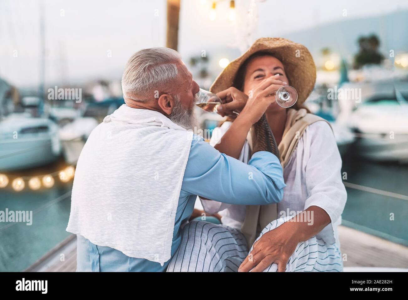 Senior couple date drinking champagne on sailboat vacation - Happy elderly people having fun celebrating wedding anniversary on boat trip Stock Photo