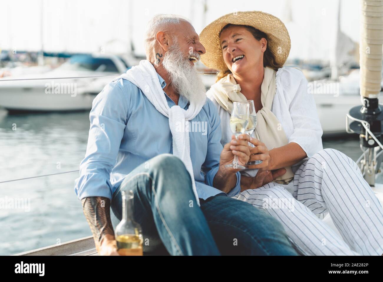 Senior couple toasting champagne on sailboat vacation - Happy elderly people having fun celebrating wedding anniversary on boat trip Stock Photo