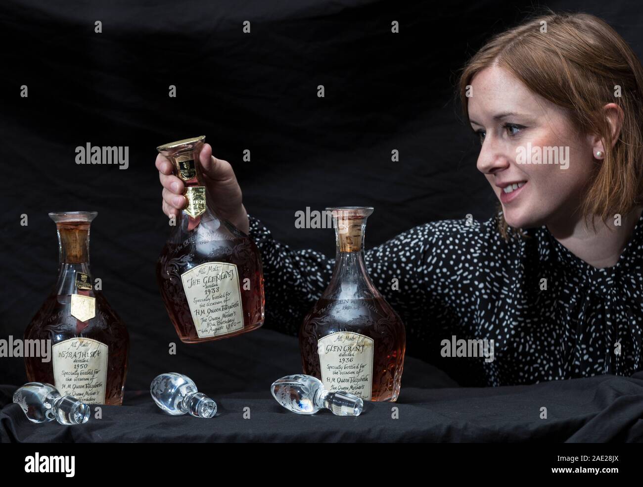 Edinburgh, United Kingdom. 06 December, 2019 Pictured: Georgina Porteous of Bonhams with three bottles of whisky bottled by Gordon & MacPhail to celebrate H.M. Queen Elizabeth, The Queen Mother’s 80th Birthday in 1980 at the Bonhams Whisky Auction. The Bonhams Whisky Auction takes place in Edinburgh on Tuesday 10 December. The sale is from a single owner collection consisting of over 1,100 bottles including The Macallan Millennium Decanter-50 year old-1949 (estimate £23,000-25,000). Credit: Rich Dyson/Alamy Live News Stock Photo