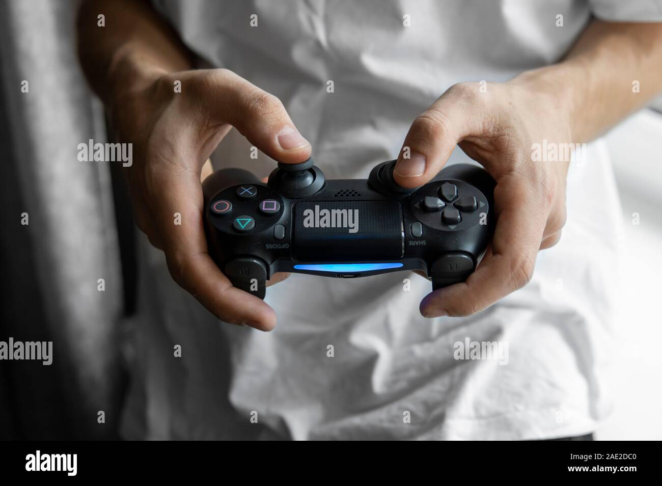 Gamer in white tshirt holding a gamepad in hands. Man hands playing a video  game with a black controller. Play a video game at home with a pleasure  Stock Photo - Alamy