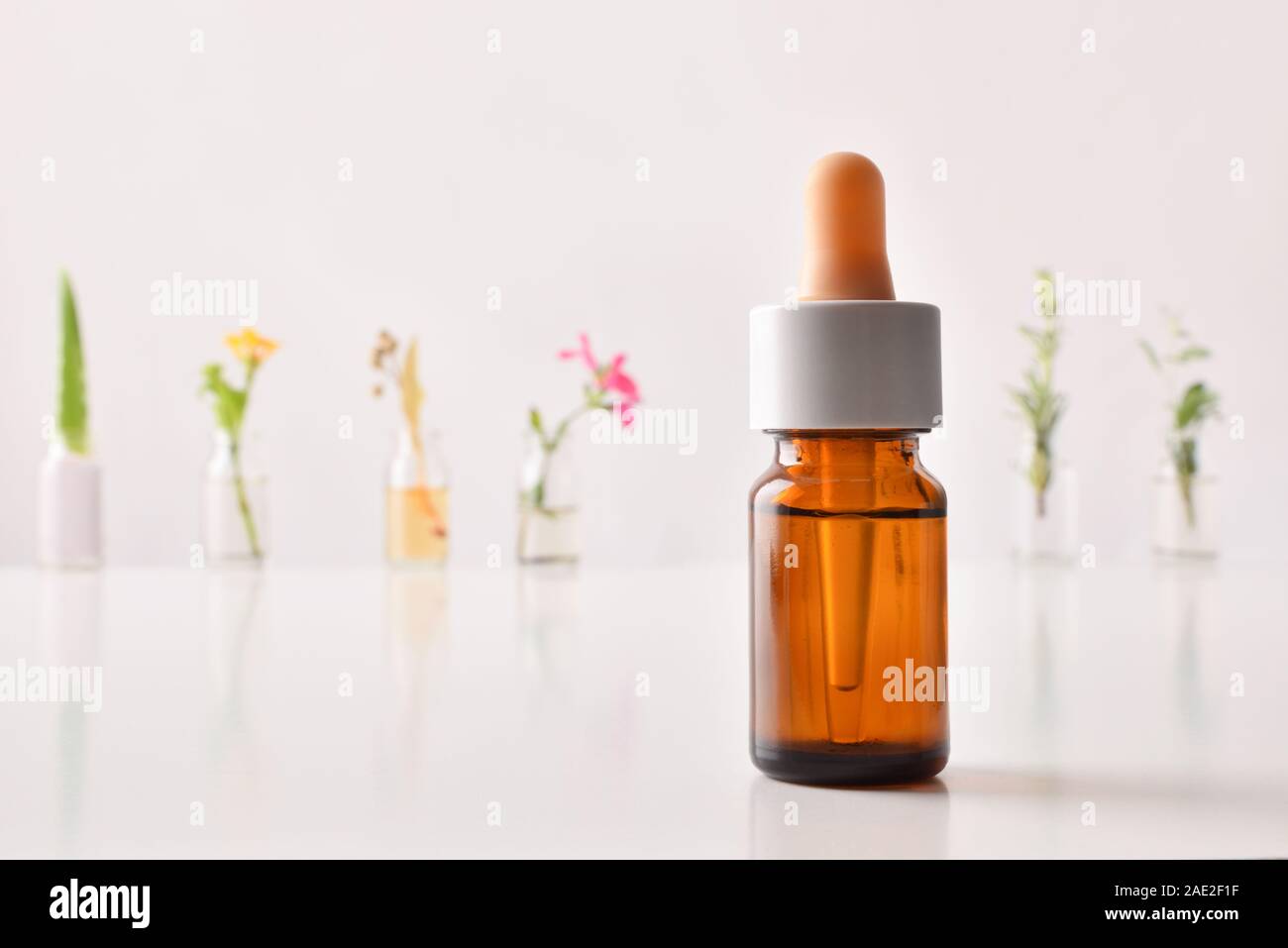 Natural medicine concept with deopper and bottles with plant essence on table and white background. Horizontal composition. Front view. Stock Photo