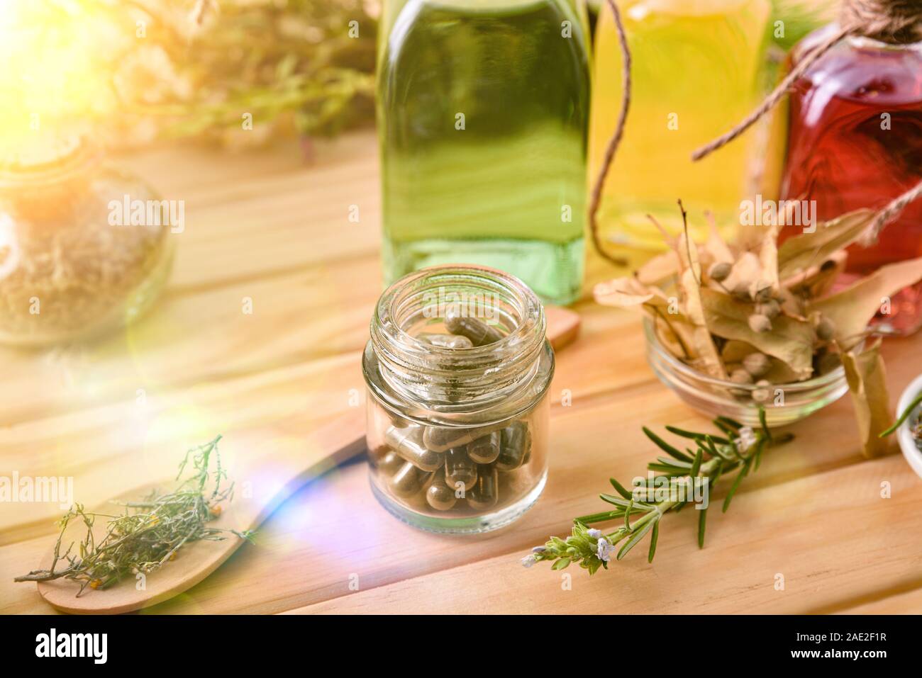 Capsules and bottles of essence of natural medicine with medicinal plants on wooden table detail. Elevated view. Horizontal composition. Stock Photo