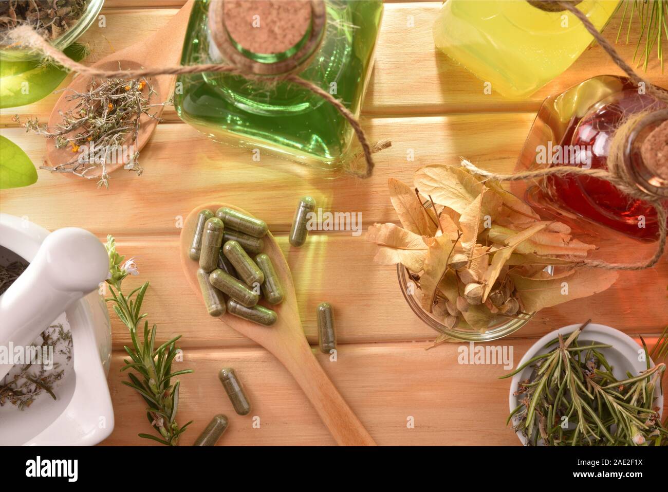 Capsules and bottles of essence of natural medicine with medicinal plants on wooden table detail. Top view. Horizontal composition. Stock Photo