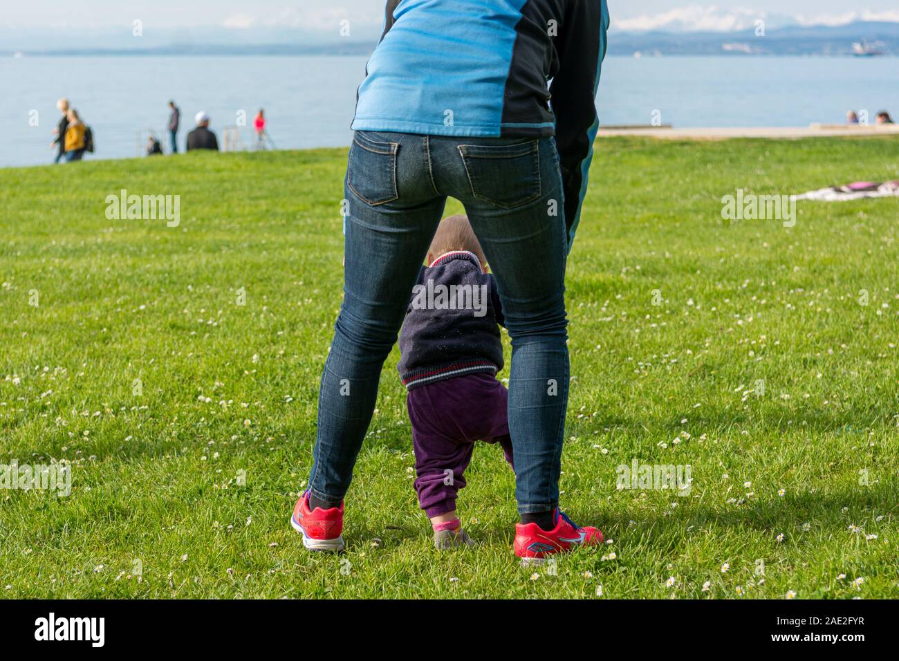 Cute baby girl learning to walk with her mother in a park Stock Photo ...