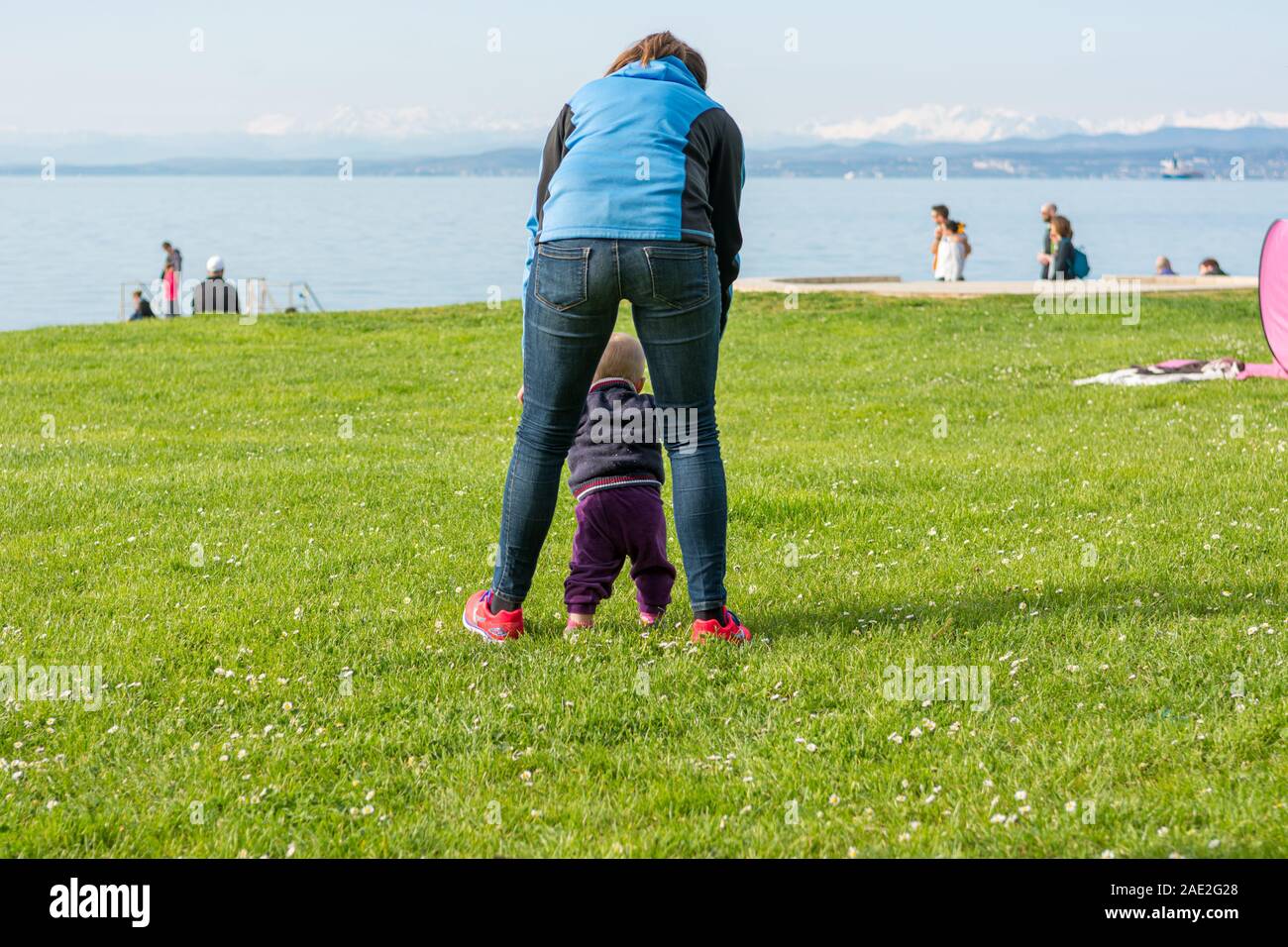Cute baby girl learning to walk with her mother in a park Stock Photo ...