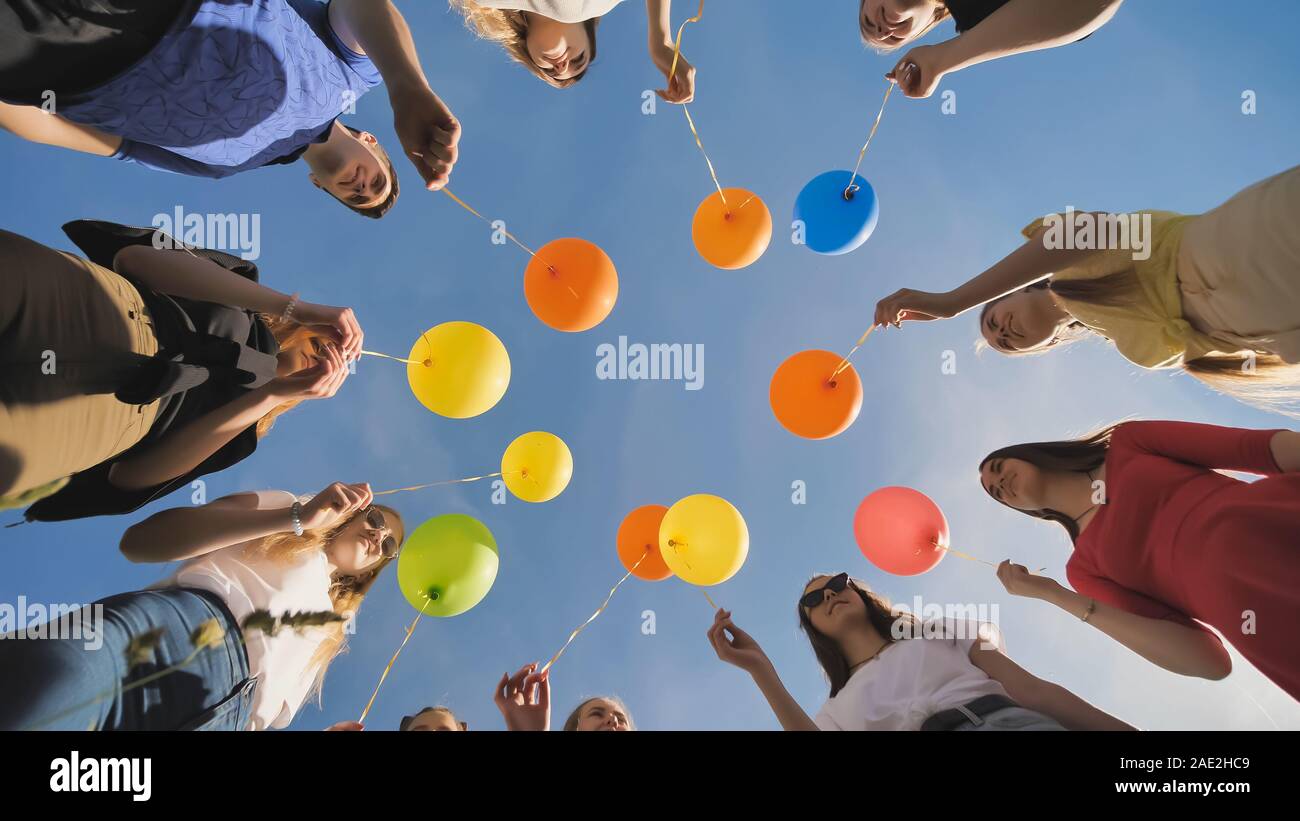 A group of friends release colorful balloons into the sky. Stock Photo