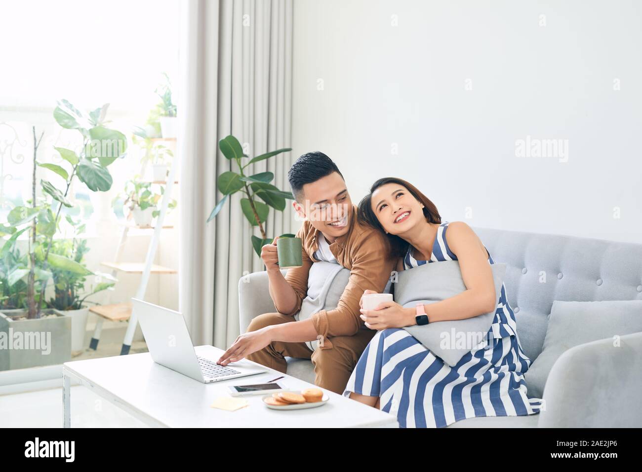 Happy young Asian Couple At Home Using Laptop Computer when sitting on ...