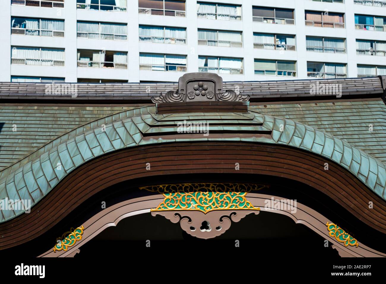 The gate of Yushima Tenmangu Shrine in Bunkyo, Tokyo, against modern apartment blocks Stock Photo