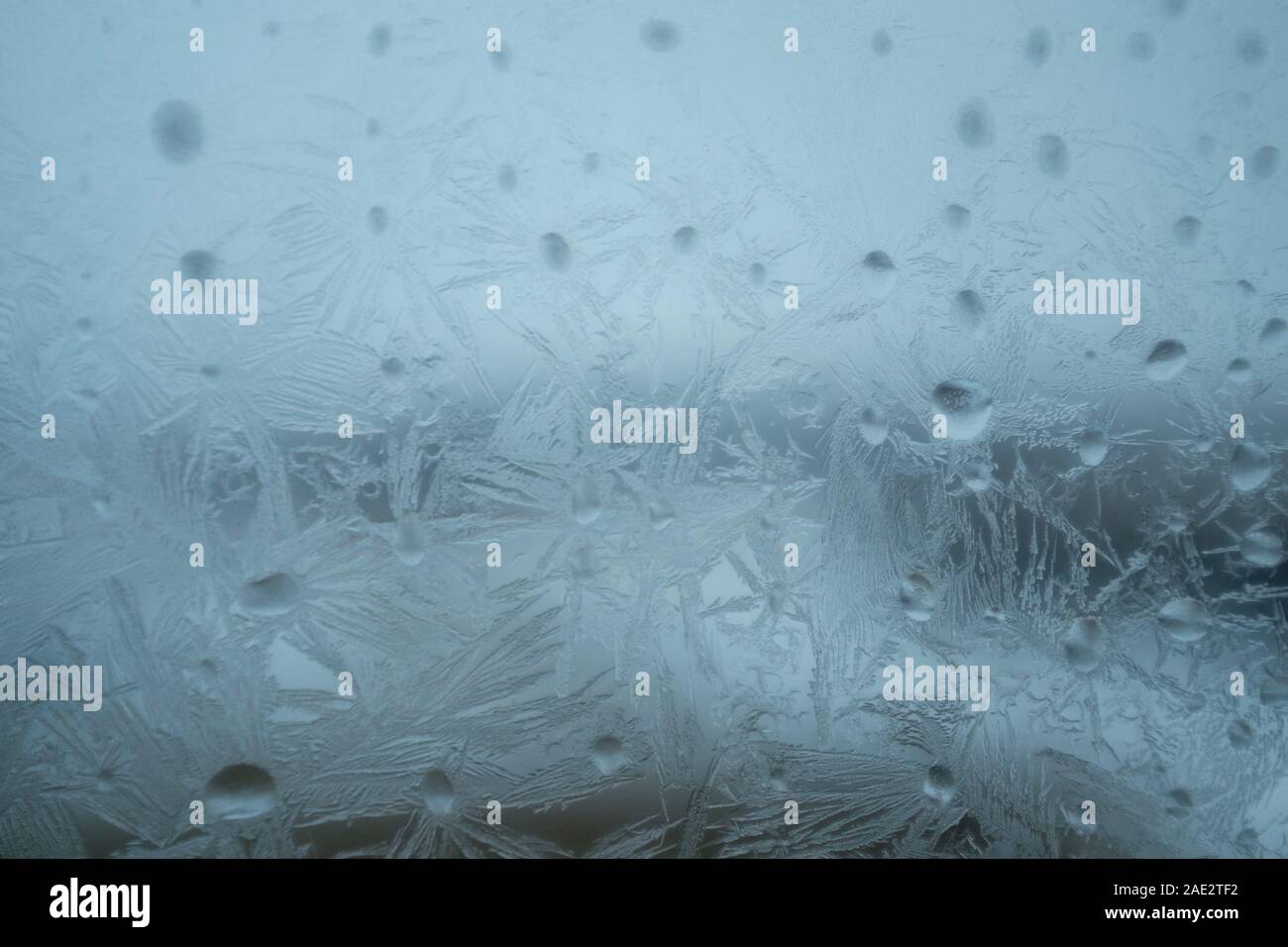 Frozen drops of water on window glass surface with frosty pattern ...
