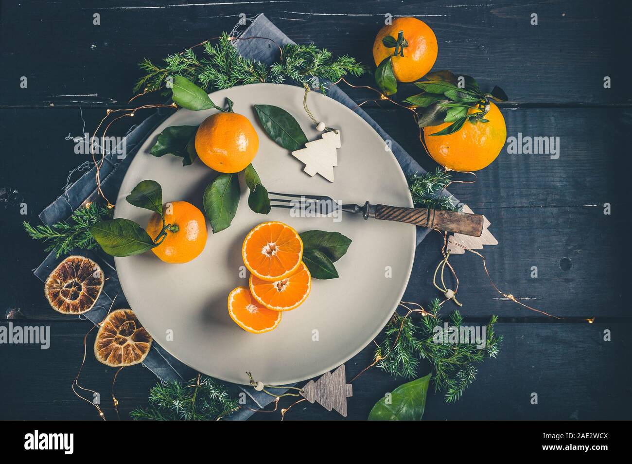 Tangerines on a festive Christmas rustic table setting with vintage dishes on a dark background. Top view Stock Photo