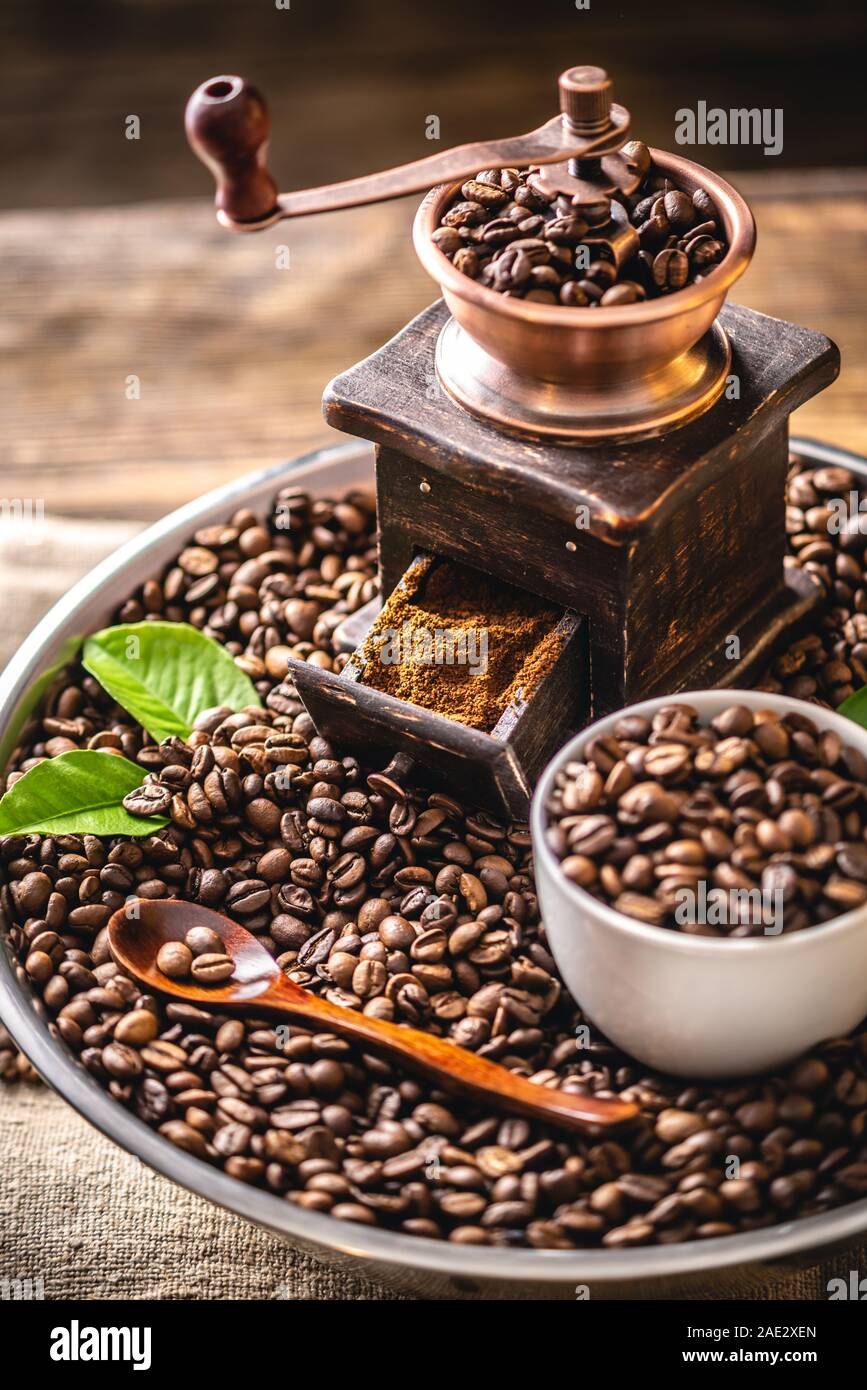 https://c8.alamy.com/comp/2AE2XEN/wooden-vintage-hand-coffee-grinder-and-cup-on-a-pile-of-brown-coffee-beans-grinding-fragrant-freshly-roasted-coffee-2AE2XEN.jpg