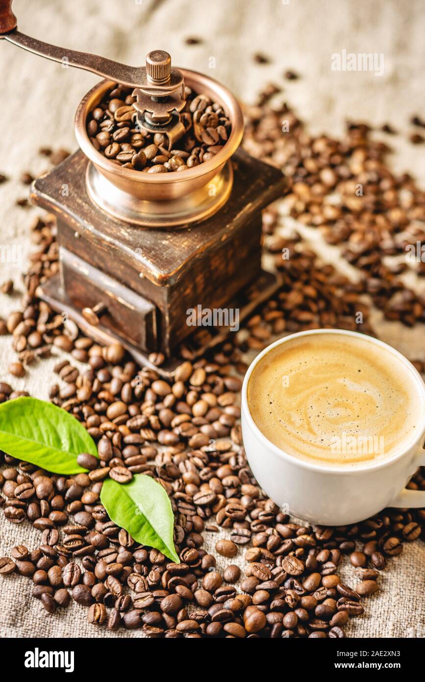 https://c8.alamy.com/comp/2AE2XN3/a-cup-of-coffee-with-foam-and-a-wooden-vintage-coffee-grinder-fragrant-invigorating-drink-from-freshly-roasted-coffee-beans-2AE2XN3.jpg